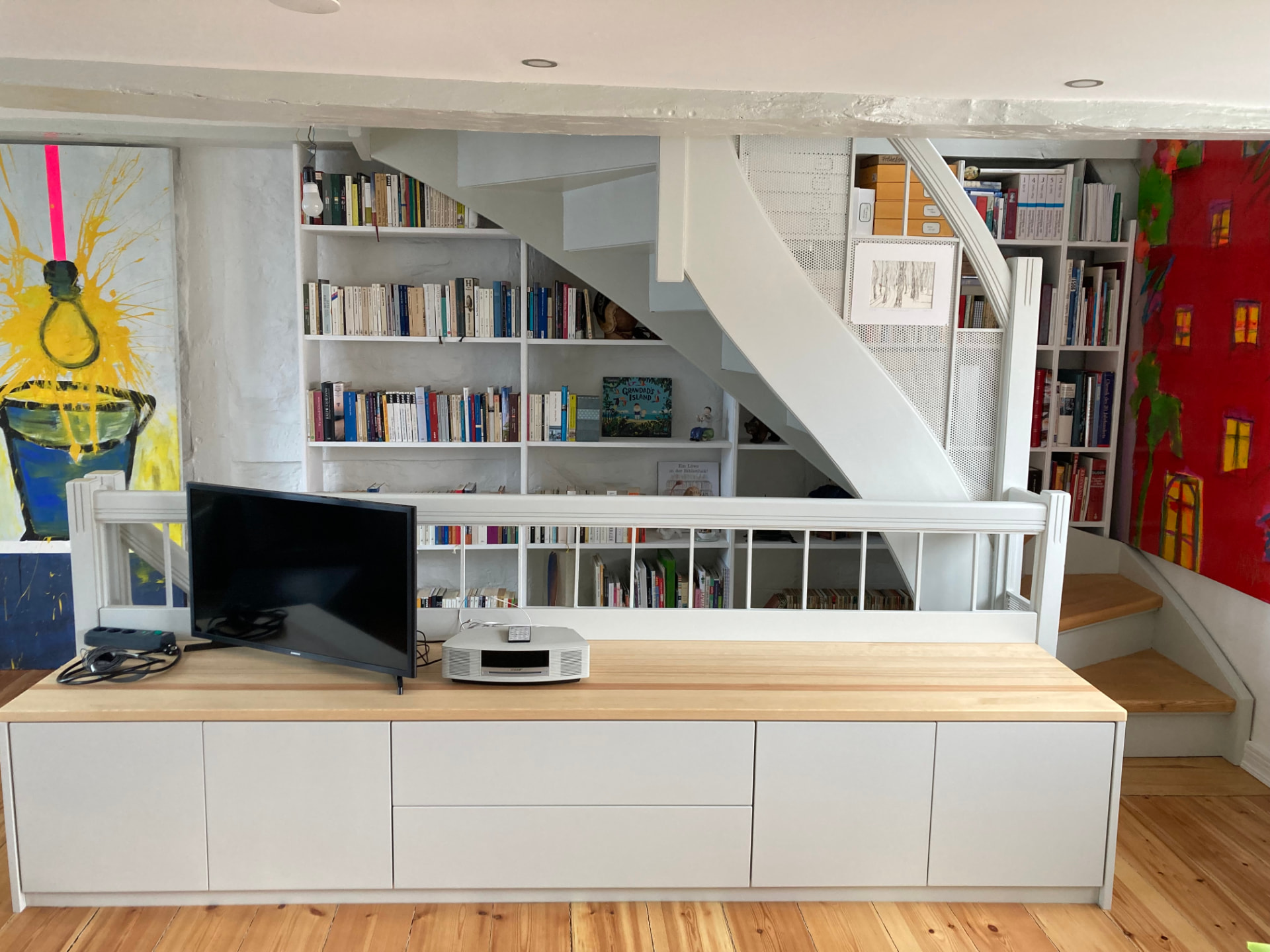 Sideboard mit Massivholzplatte vor Bücherwand und Treppe