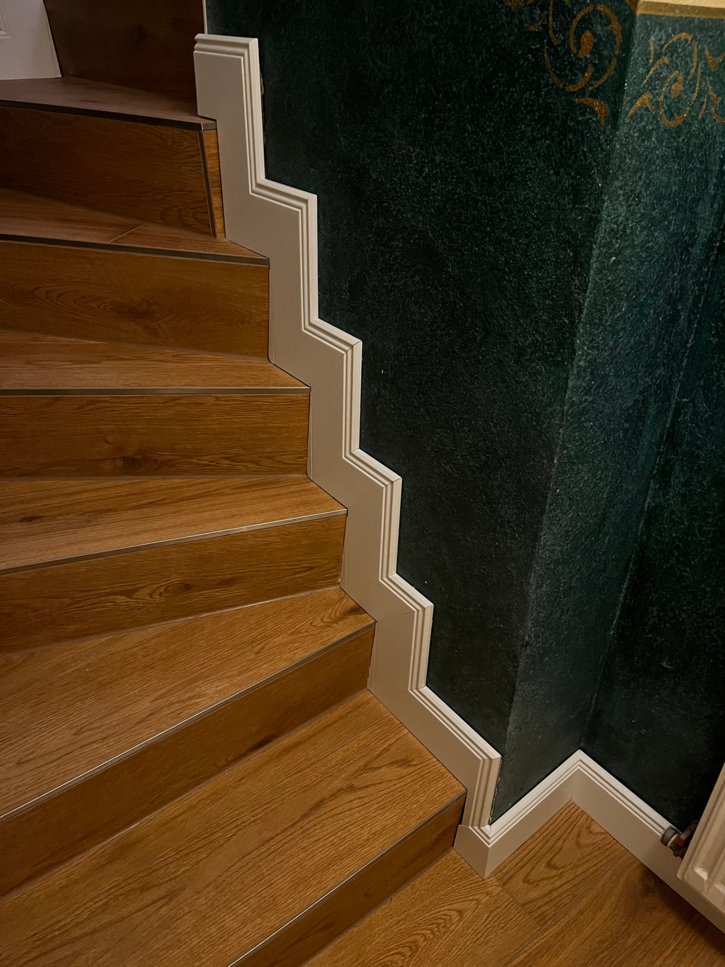 Treppe mit Holzstufen und maßgefertigten, gestuften Sockelleisten